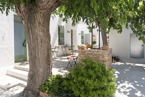 An outdoor seating area with a table and chairs, surrounded by greenery and a tree. - Hostal Cling 43 (Deltebre)
