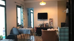 A dining area with a table and chairs, a television mounted on the wall, and a ceiling with exposed wooden beams. - Hostal Cling 43 (Deltebre)