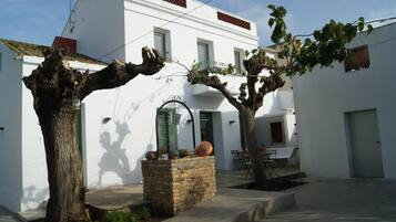 Un edificio blanco con una jardinera de piedra y dos árboles en el patio.