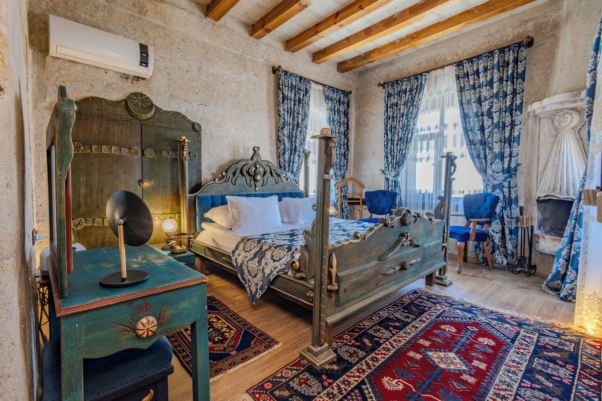 A traditional room with a bed, a wooden wardrobe, a mirror, and a blue chair.
