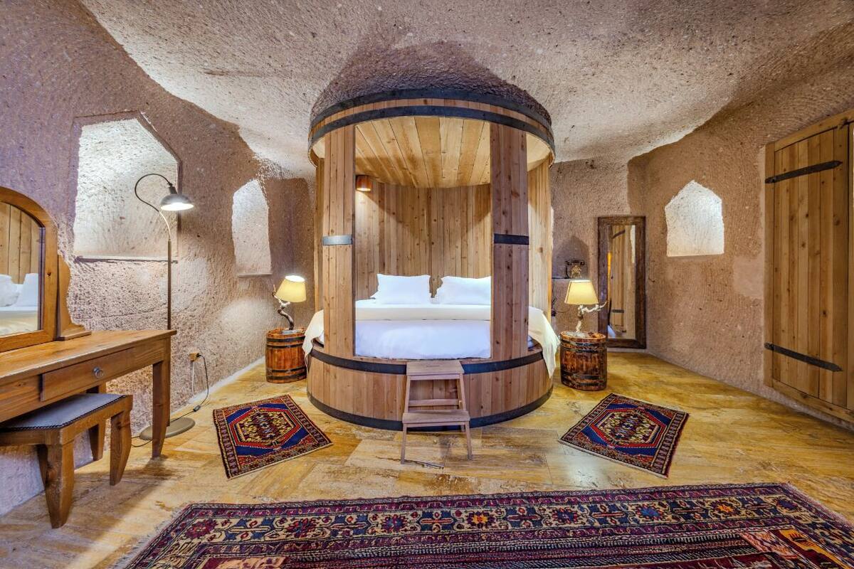 A circular wooden room with a bed, wooden furniture, and rugs.