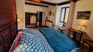 A bedroom with a bed, a wooden headboard, a desk, and a window with curtains. - Le Sareymond (Chatillon-en-Diois)