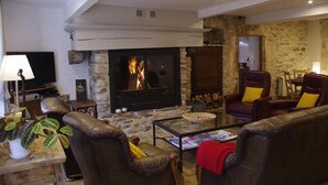 A cozy living room with a stone fireplace, leather sofas, and a television. - Le Sareymond (Chatillon-en-Diois)
