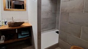 A bathroom with a stone sink, wooden vanity, tiled walls, and a wooden stool. - Le Sareymond (Chatillon-en-Diois)