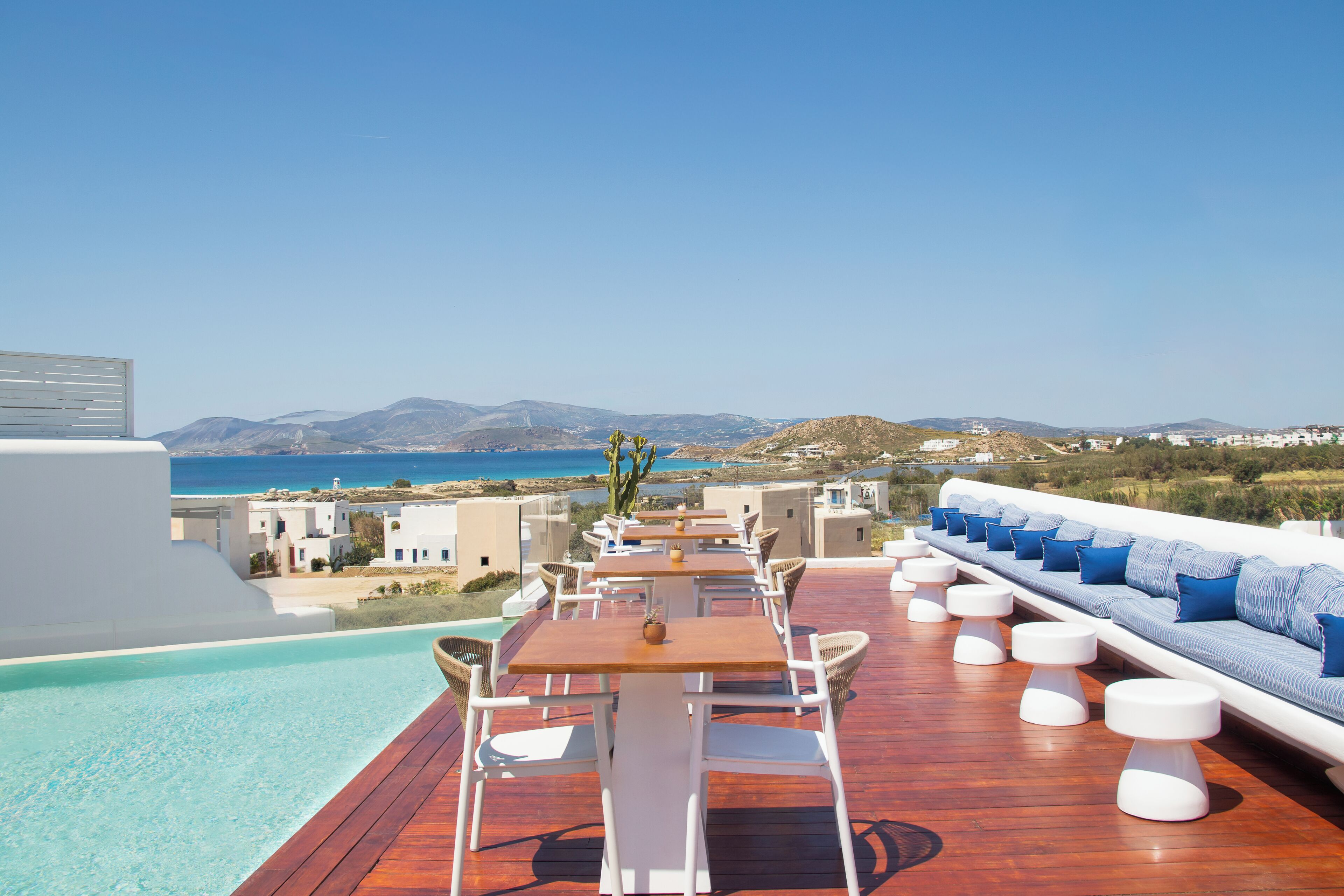 Una terraza en la azotea con piscina, zona de estar y vistas al mar y colinas.