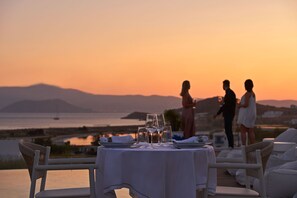 A table set for two with a view of the sea and mountains at sunset. - 18 Grapes Hotel (Naxos)