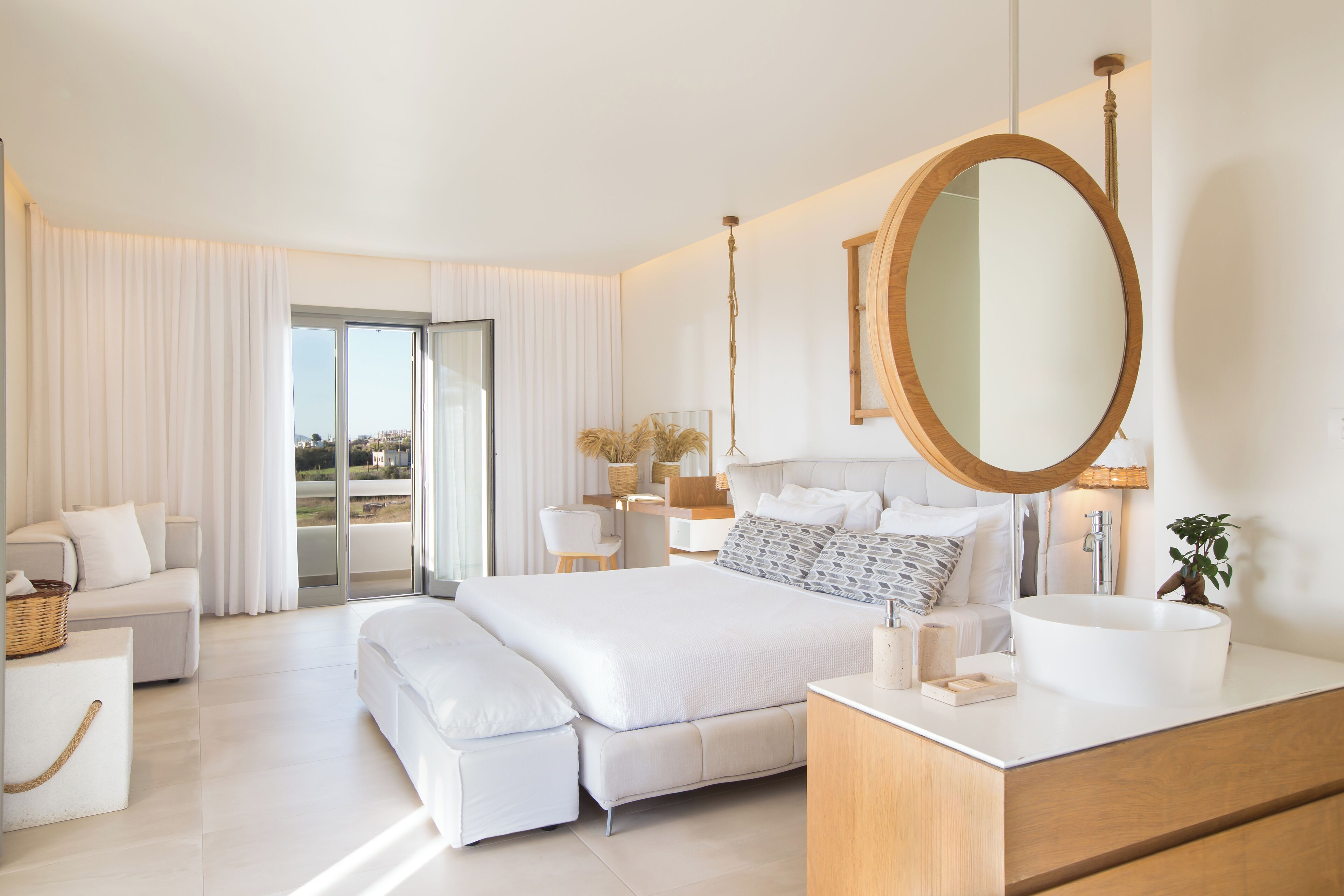 Une chambre à coucher moderne avec un grand lit, une coiffeuse avec un miroir et une vue sur l’extérieur grâce à une porte coulissante.