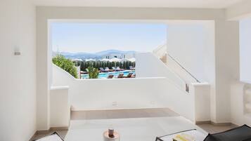 Une chambre moderne avec vue sur une piscine et des montagnes, comprenant un mur blanc, une petite table et une chaise.