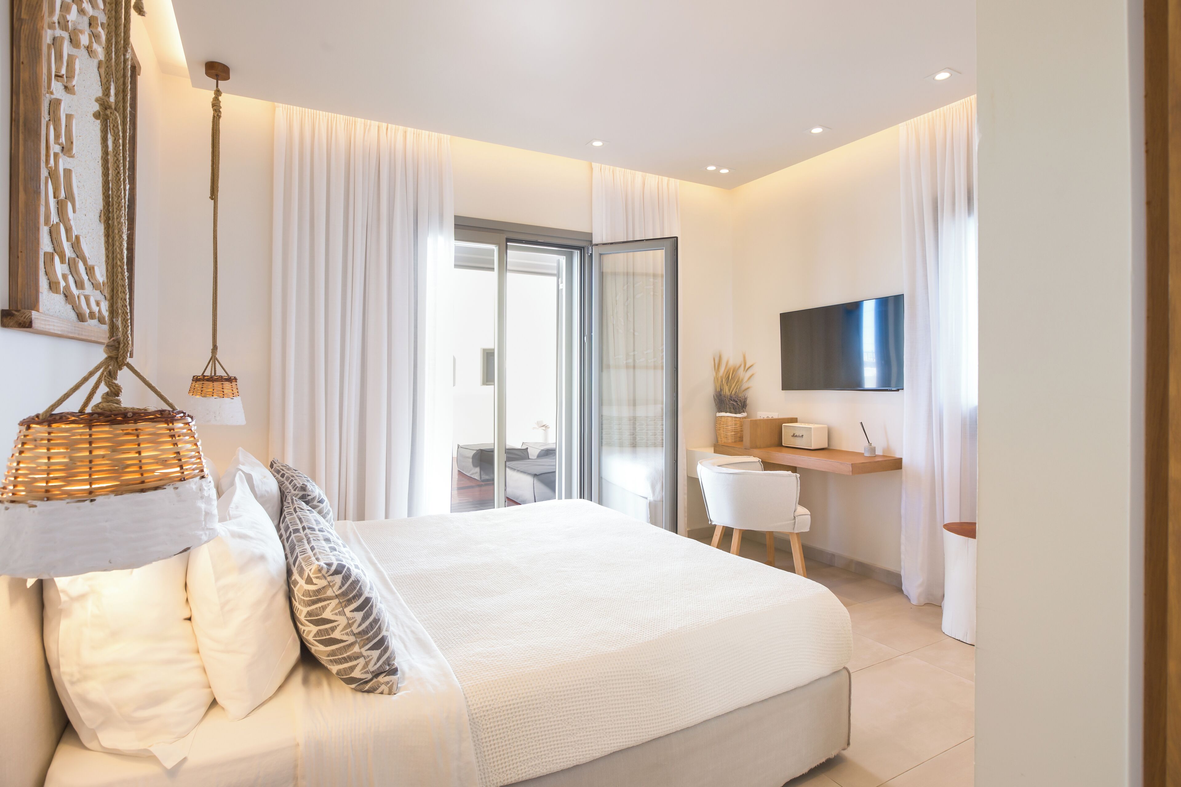 A modern bedroom with a large bed, a desk, and a TV.
