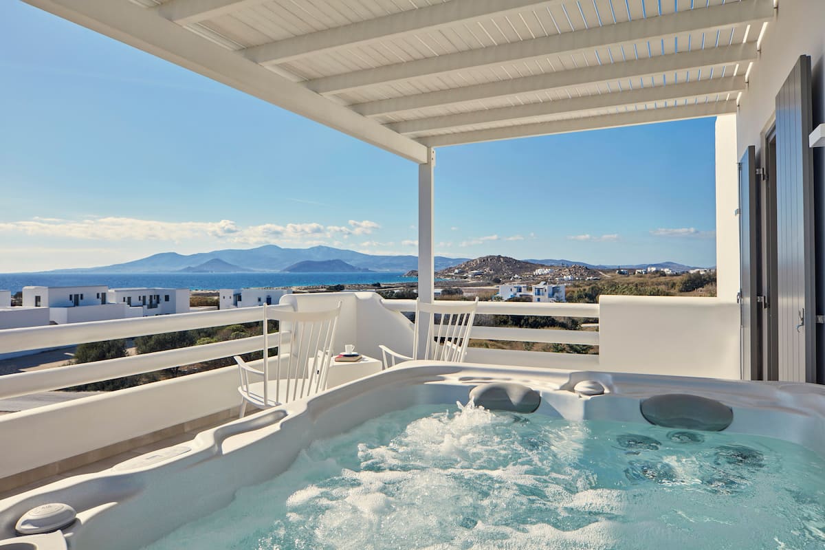 A hot tub on a balcony with a view of the sea and mountains.