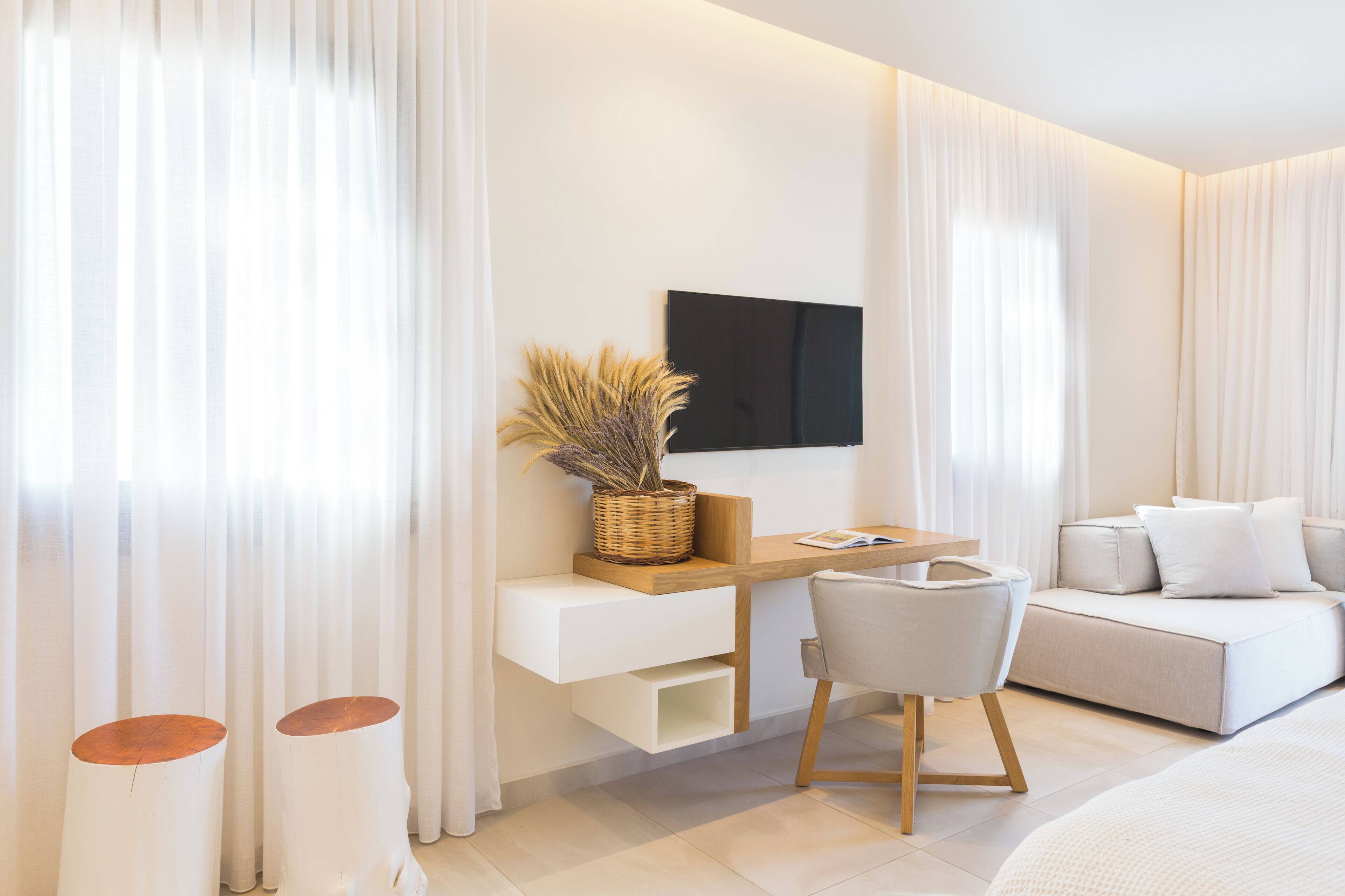 Una habitación de hotel moderna con una cama, un sofá, un escritorio con una silla y un televisor montado en la pared.
