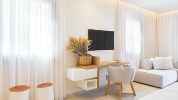 Una habitación de hotel moderna con una cama, un sofá, un escritorio con una silla y un televisor montado en la pared.