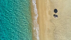 An aerial view of a beach with clear turquoise water and a sandy shore. - 18 Grapes Hotel (Naxos)