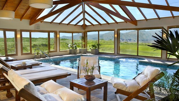 A pool area with lounge chairs and a view of the landscape. - Chamonix Posada y Spa (Villa General Belgrano)