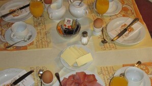 A breakfast table set with plates, bread, eggs, cheese, ham, and various condiments. - Neuenkirchener Hof (Neuenkirchen)