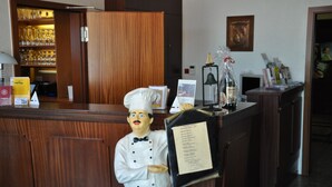 A reception area with a wooden counter, a menu board, and a glass display case with items. - Neuenkirchener Hof (Neuenkirchen)