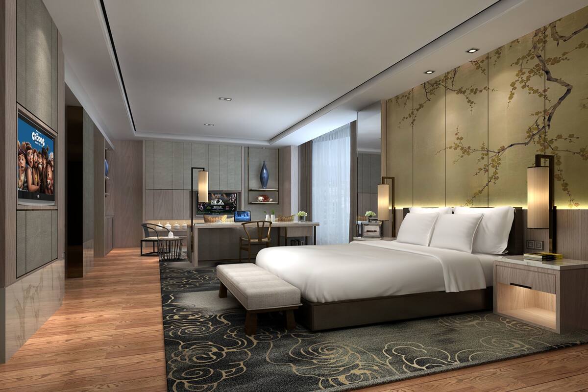 Une chambre d’hôtel moderne avec un grand lit, un bureau, une télévision et un mur décoratif.