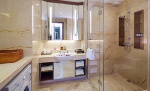A modern bathroom with a glass-enclosed shower, a marble sink, and a built-in towel rack.