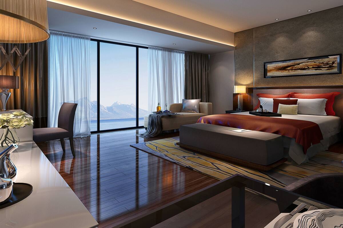Une chambre d’hôtel moderne, dotée d’un grand lit, d’un bureau, d’une chaise et offrant une vue sur les montagnes par la fenêtre.