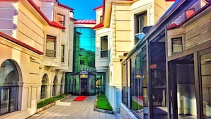 A modern building with a central courtyard, large windows, and a red carpet path. - Kars-i Sirin Hotel (Kars)