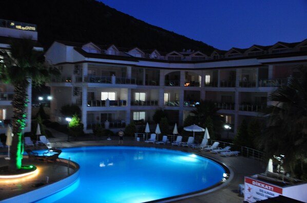 Un hotel con piscina, varios balcones y sillones de descanso.
