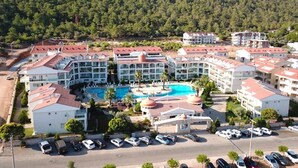 A hotel with multiple buildings, a central swimming pool, and a mountainous backdrop. - Akbük Palace Hotel & Residence (Didim)