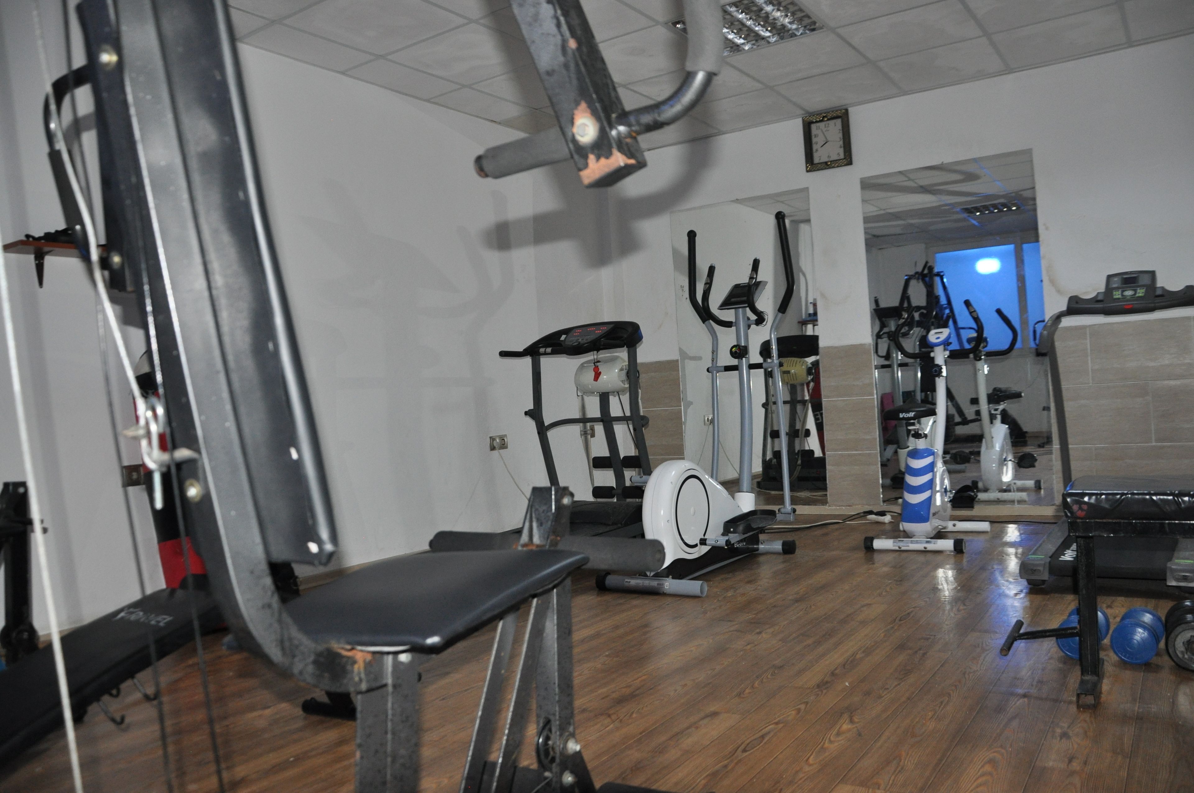 Un gimnasio con equipos de ejercicio variados, incluyendo una máquina de remo, una elíptica y una bicicleta estática.