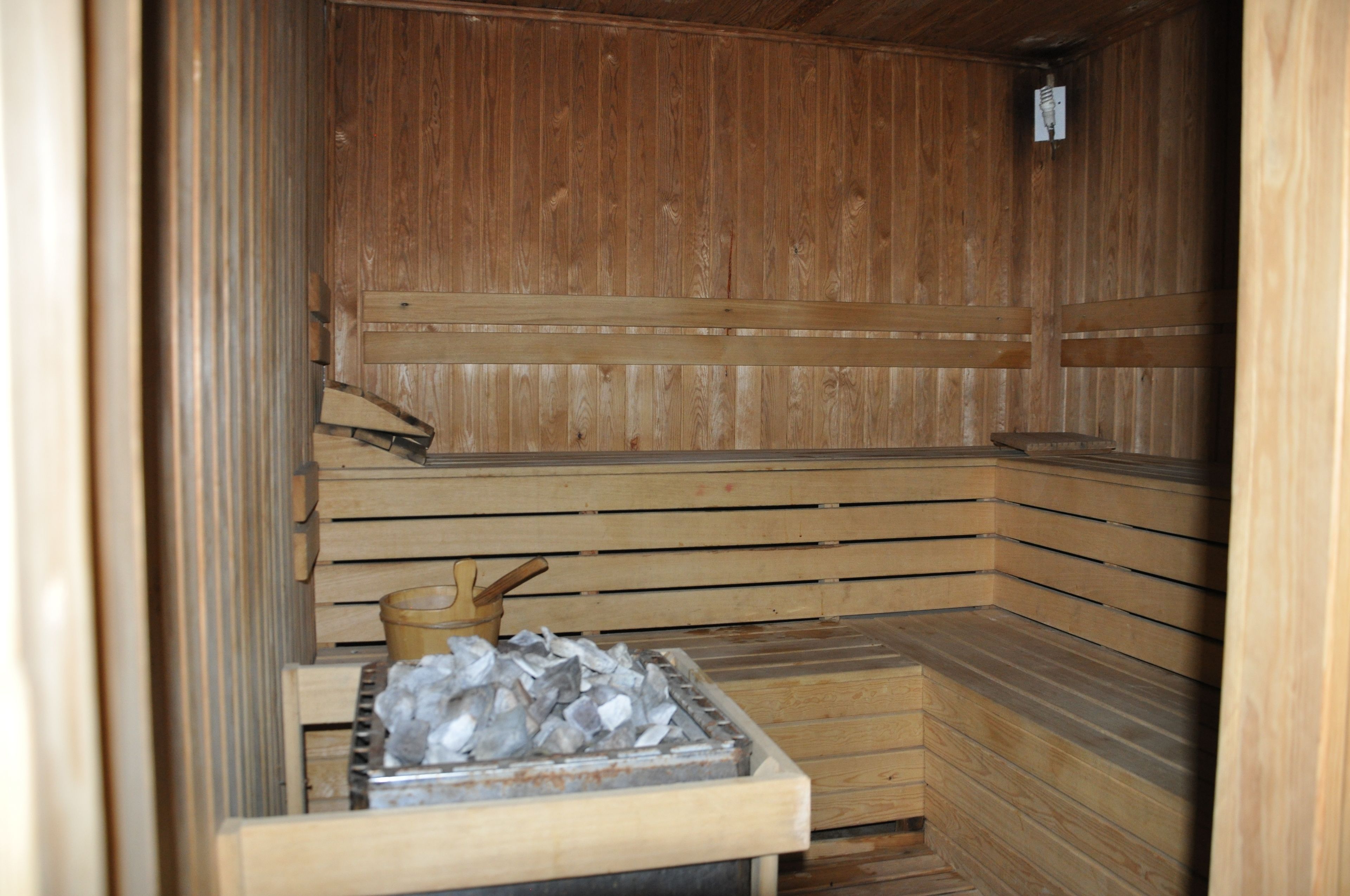 Una sauna con bancos de madera y un recipiente metálico con hielo.