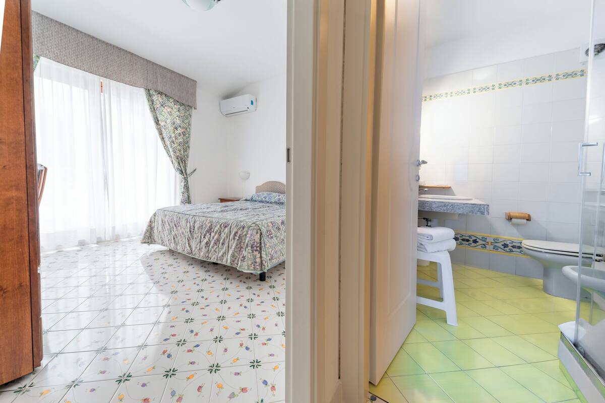 A bedroom with a bed, a bathroom with a toilet, and a shower area.