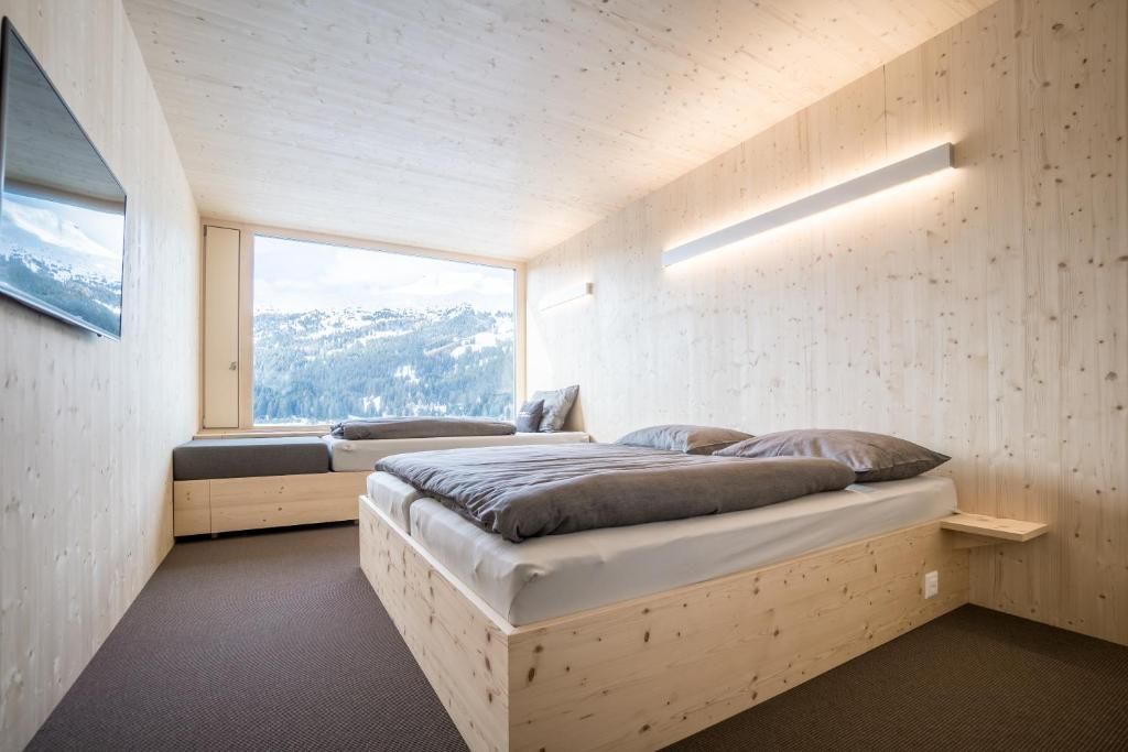 A bedroom with a bed, a window seat, and a view of a snowy landscape.