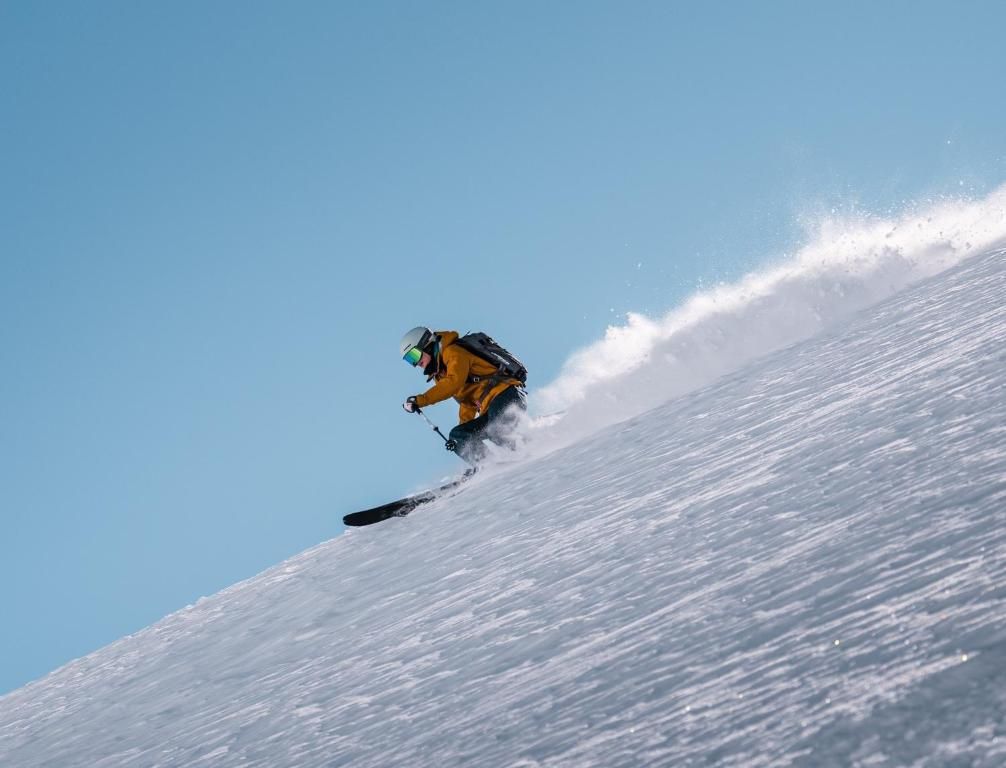 Eine Person gleitet auf einem Snowboard eine steile Piste hinab.