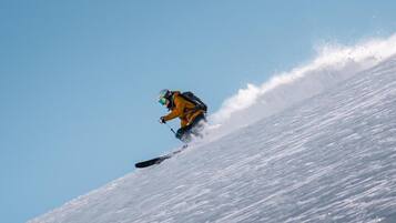 Eine Person gleitet auf einem Snowboard eine steile Piste hinab.