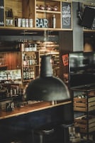 A bar area with shelves stocked with bottles, a sign reading 'Havana Mojito,' and a hanging light fixture.