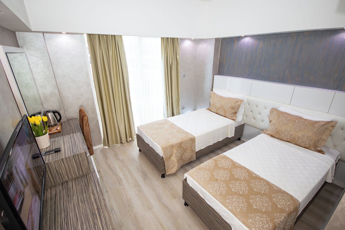 Una habitación de hotel con dos camas, televisión, escritorio y espejo.