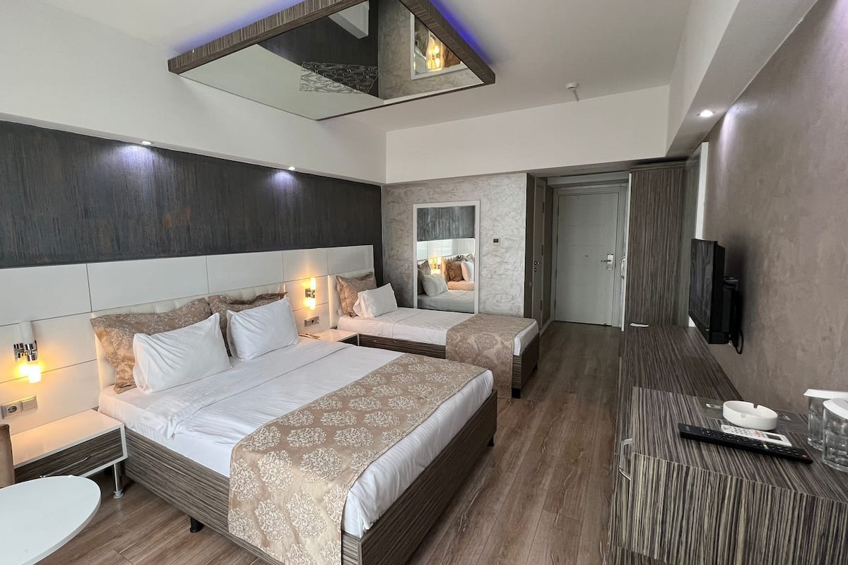 Una habitación de hotel moderna con una cama grande, una cama más pequeña, un escritorio y un televisor.