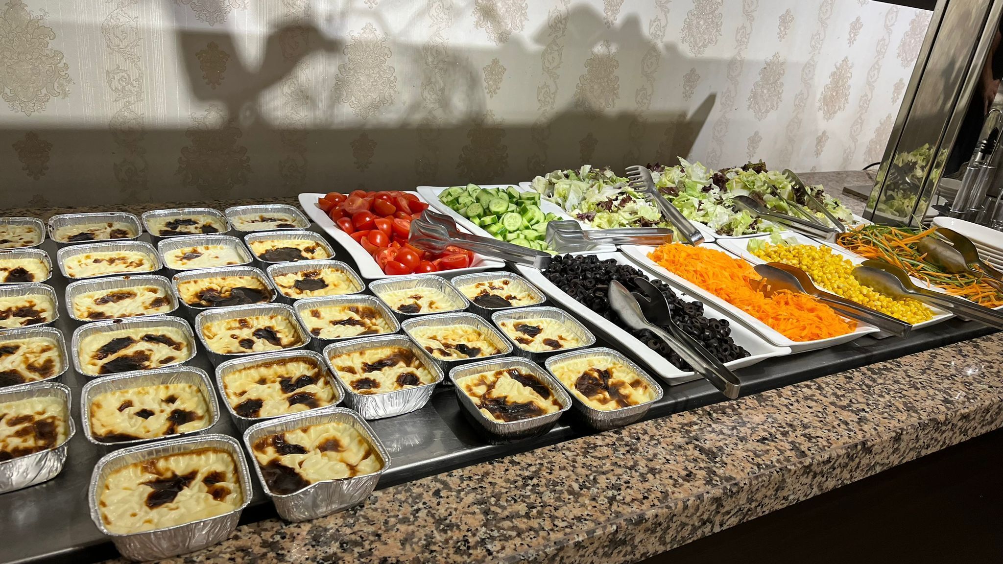 A buffet with various food options including salads, vegetables, and baked dishes.