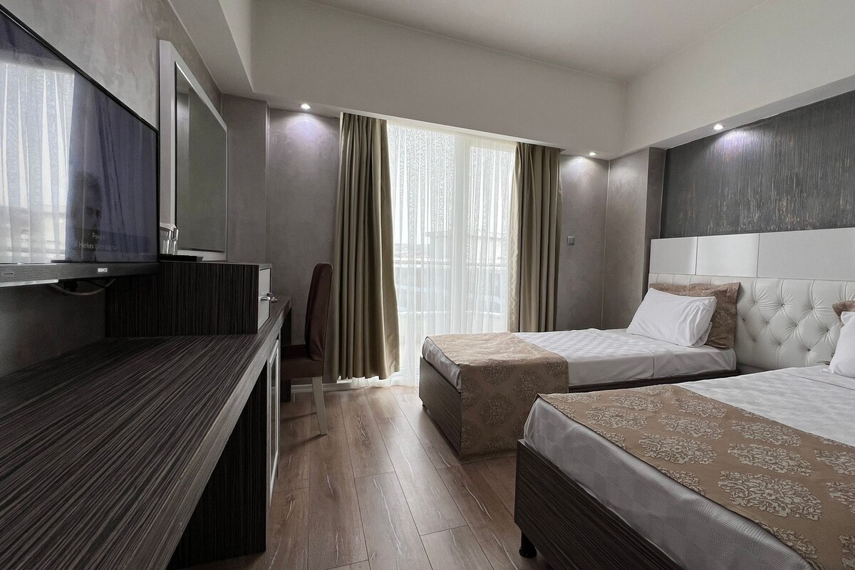 Una habitación de hotel con dos camas, un escritorio y una televisión.
