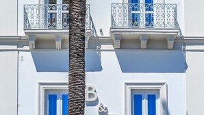 Un edificio blanco con balcones y una palmera frente a él.
