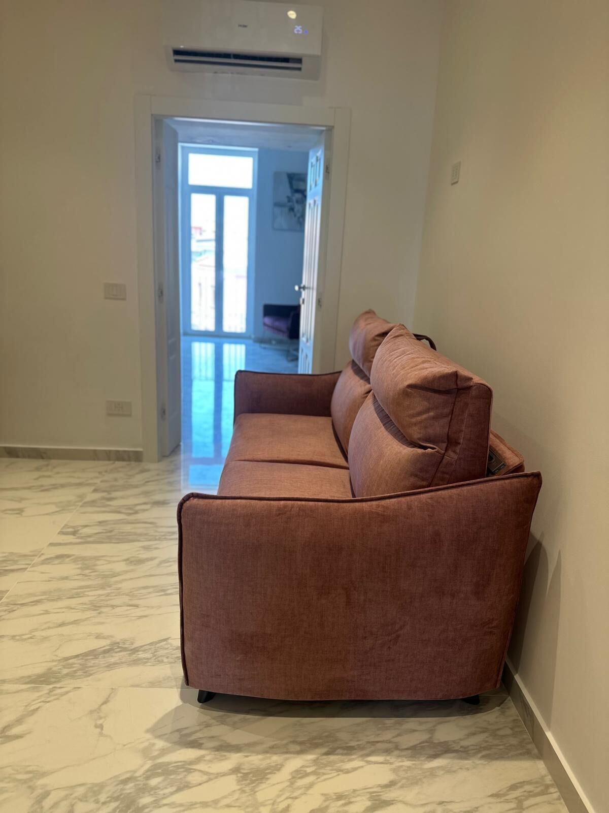 A spacious room with a brown sofa and a marble floor.