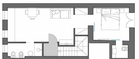 A floor plan of a hotel room with a bed, a desk, a chair, a small table, and a bathroom.