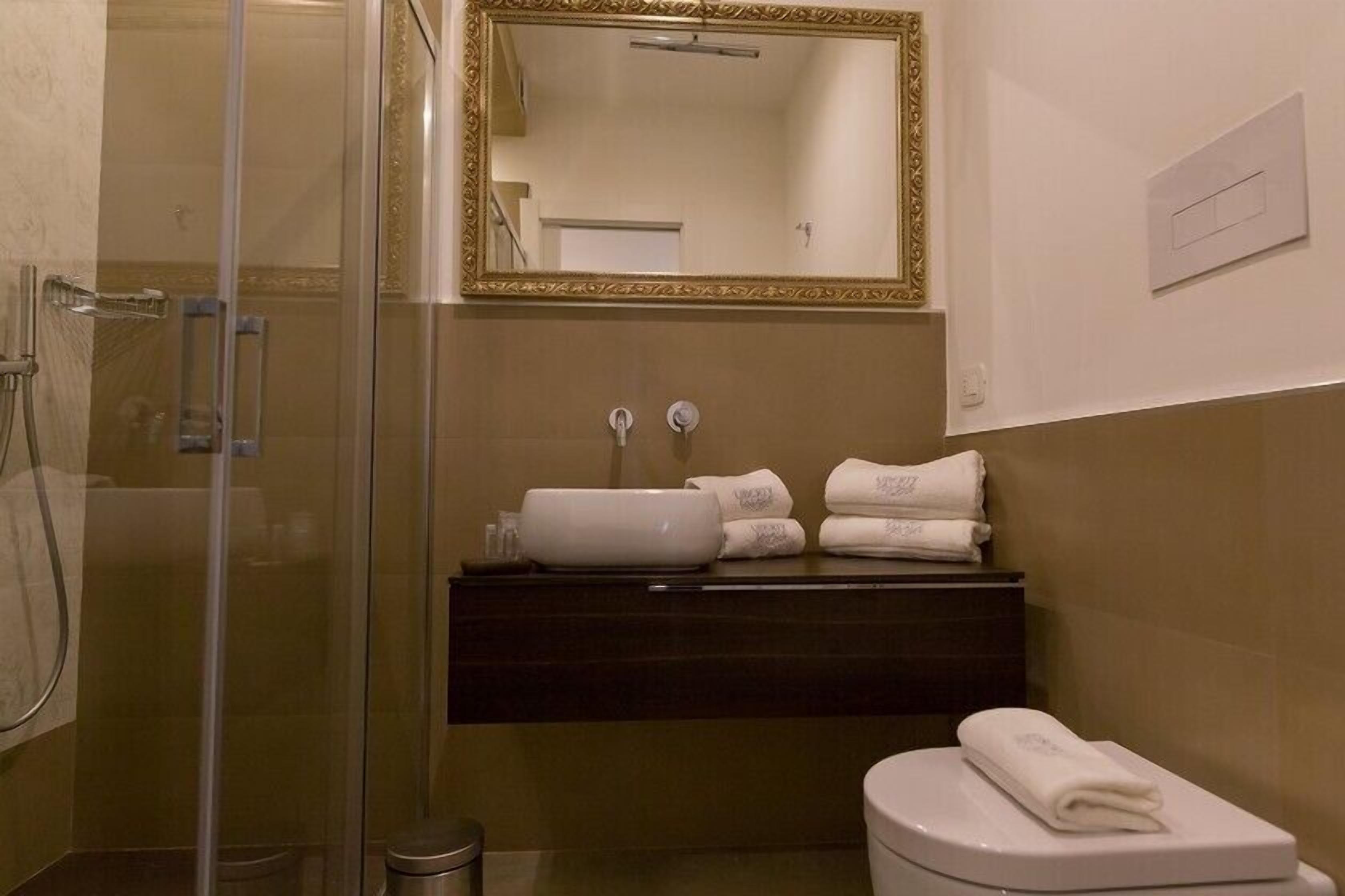 Une salle de bain avec une douche à parois de verre, un lavabo doté d’un plan de toilette foncé et des toilettes.