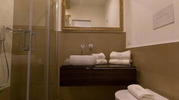 Une salle de bain avec une douche à parois de verre, un lavabo doté d’un plan de toilette foncé et des toilettes.