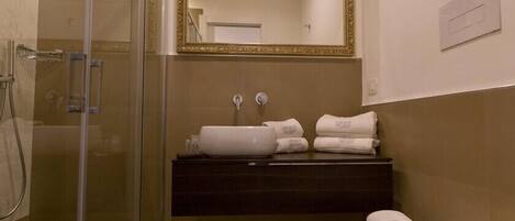 A bathroom with a glass shower enclosure, a sink with a dark countertop, and a toilet.
