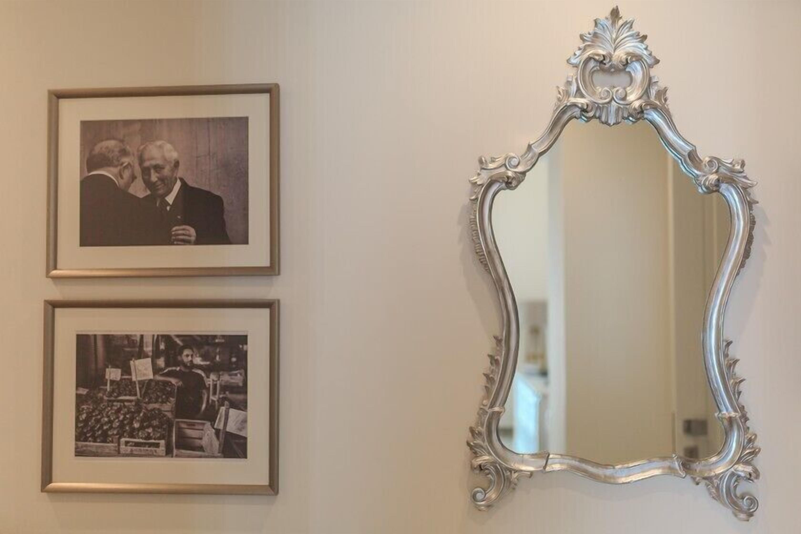 A wall with two framed photographs and an ornate mirror.