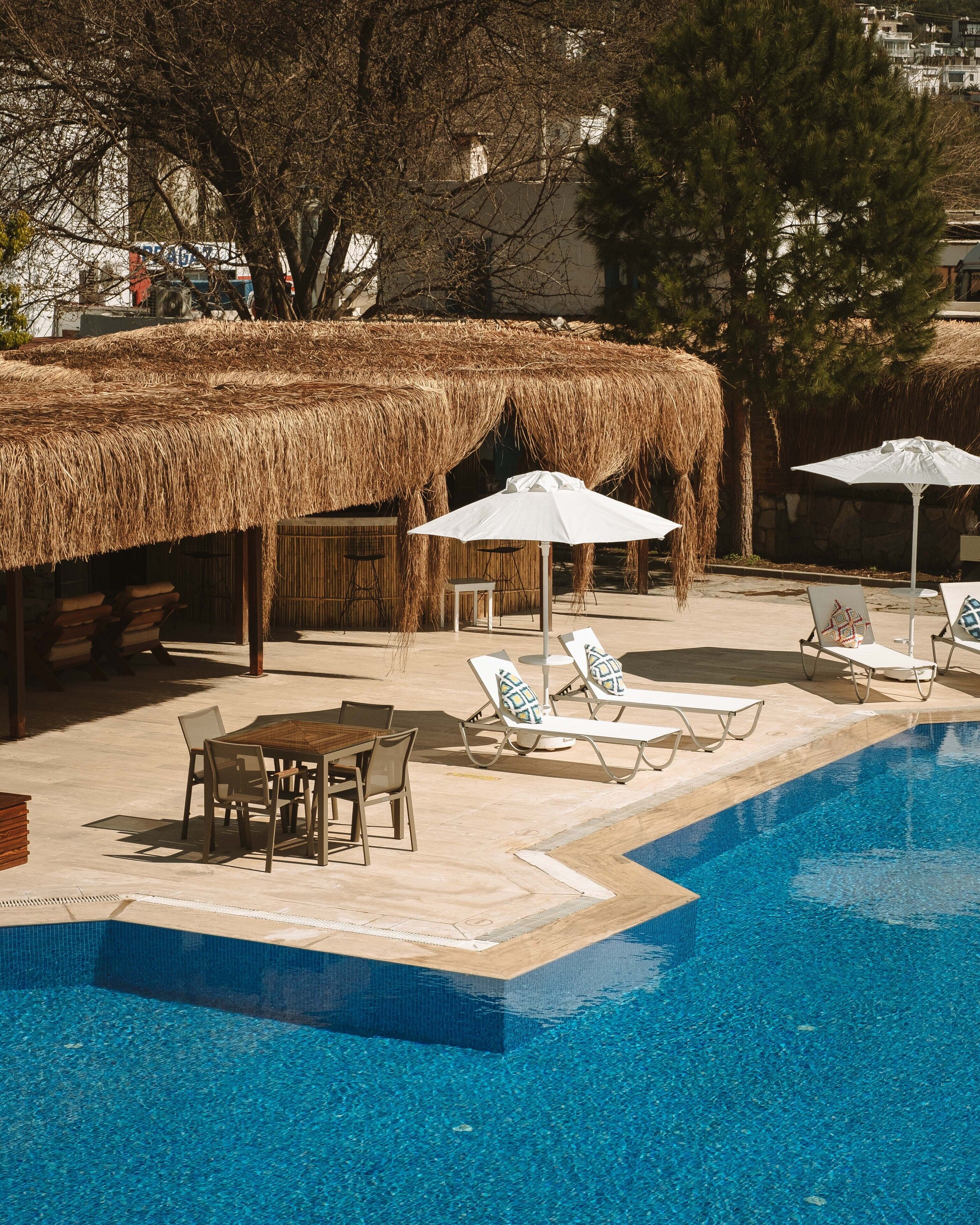 A pool area with lounge chairs, a table, and umbrellas.