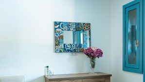 Une pièce comprenant un bureau en bois, une chaise, un canapé, un miroir orné d’un motif floral et un vase rempli de fleurs.