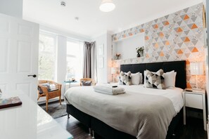 A modern hotel room with a large bed, a bedside table, a chair, and a view of the outdoors. - Sweet Suites Lytham St Annes (Lytham St. Anne's)
