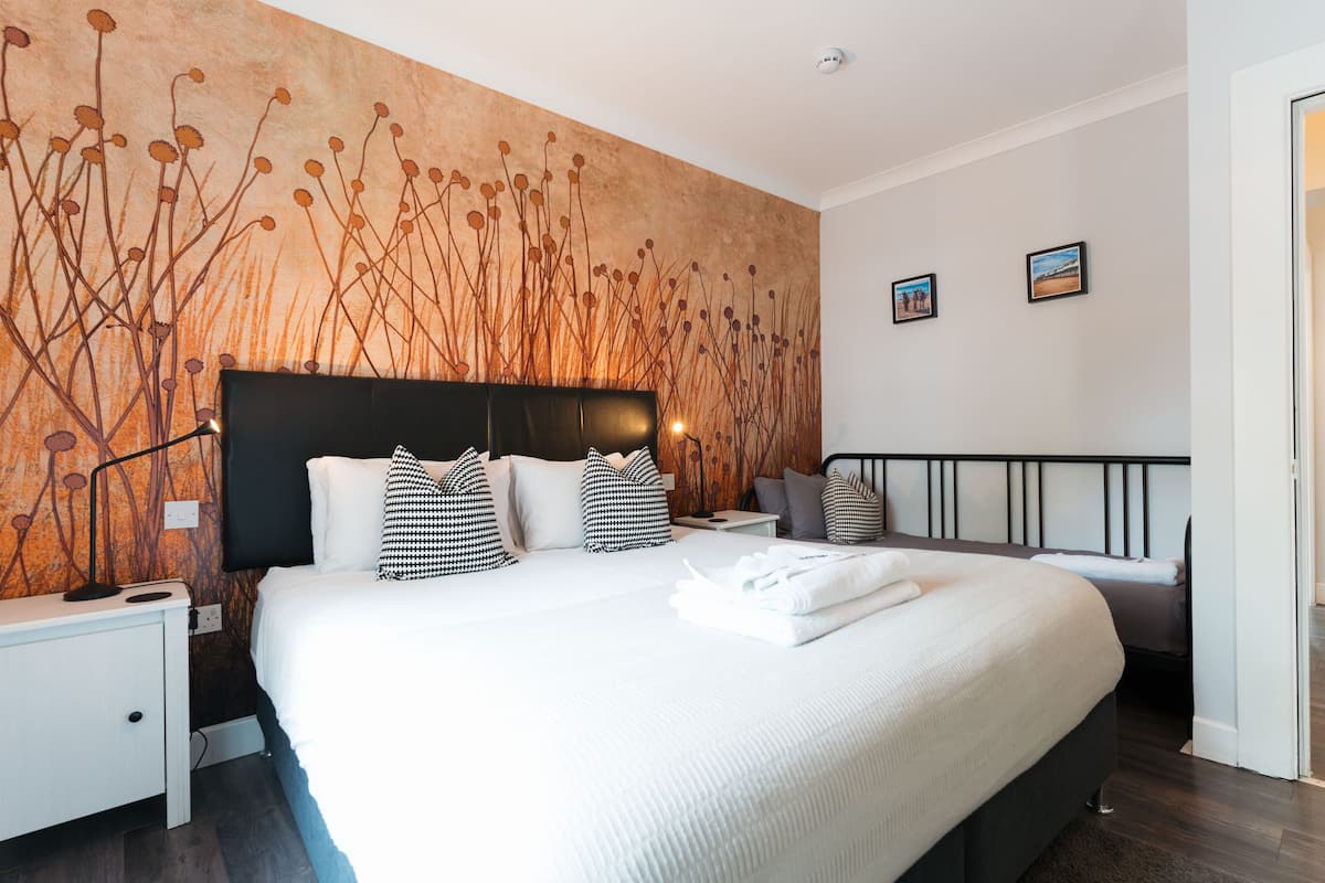Ein modernes Hotelzimmer mit einem großen Bett, einem Nachttisch und einer Wand mit strukturierter Gestaltung.