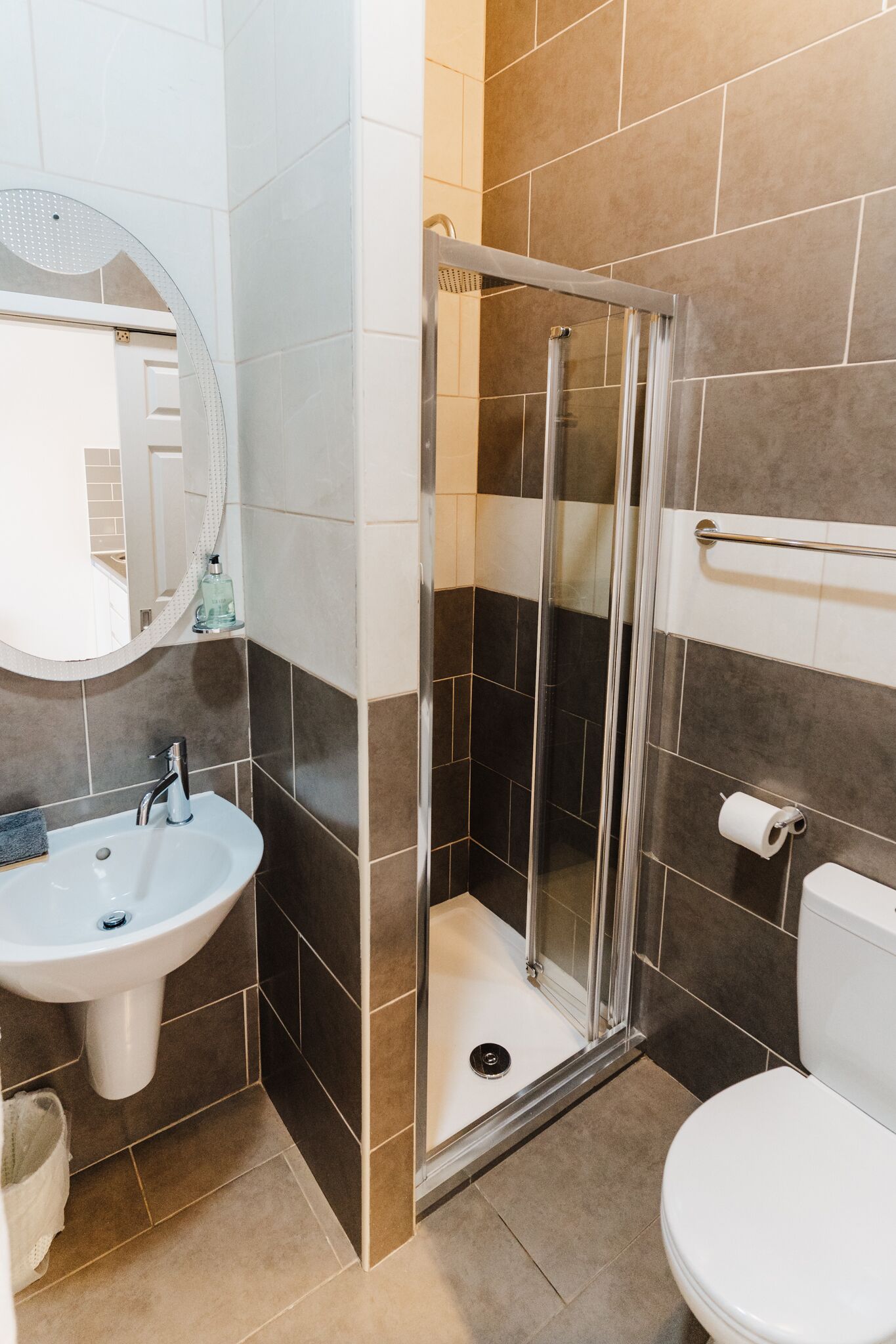 Een badkamer met een wastafel, spiegel, toilet en douchecabine.