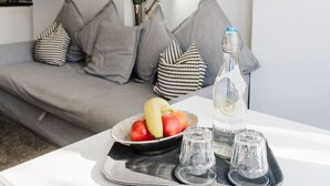 A modern living room with a grey sofa, decorative wall art, and a tray with fruits and glasses. - Sweet Suites Lytham St Annes (Lytham St. Anne's)
